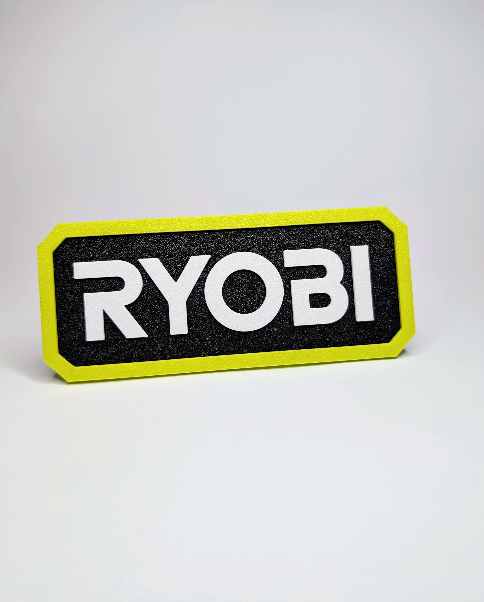 3D-printet Ryobi-skilt i sort og gult.