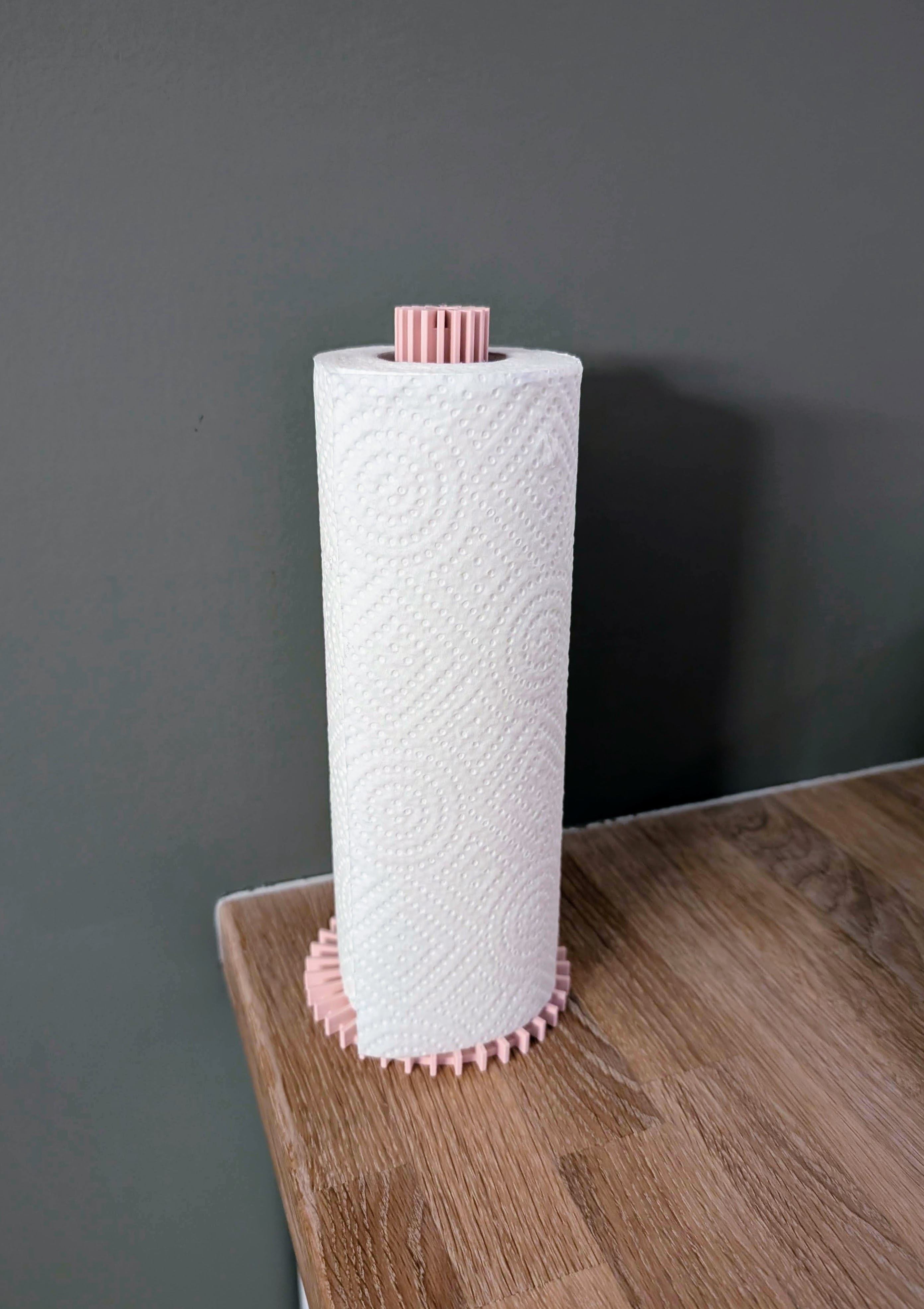 Kompakt, 3D-printet tørkerullholder med tannhjul-design i rosa.